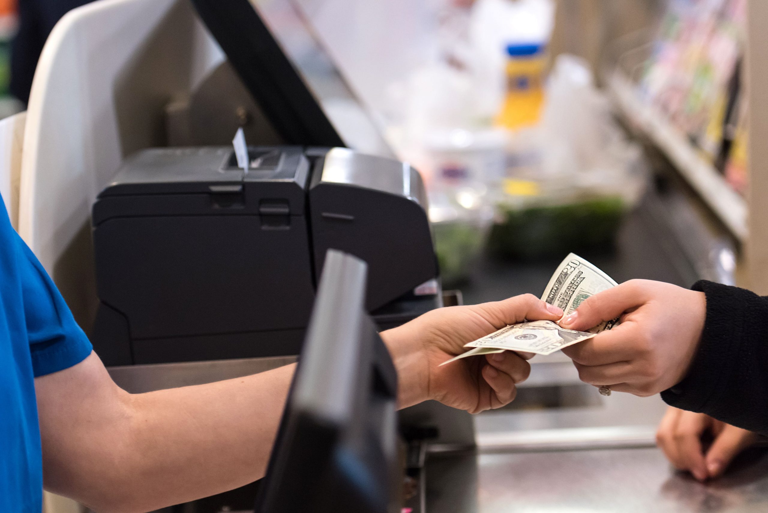 Person handing cash to cashier at a grocery store