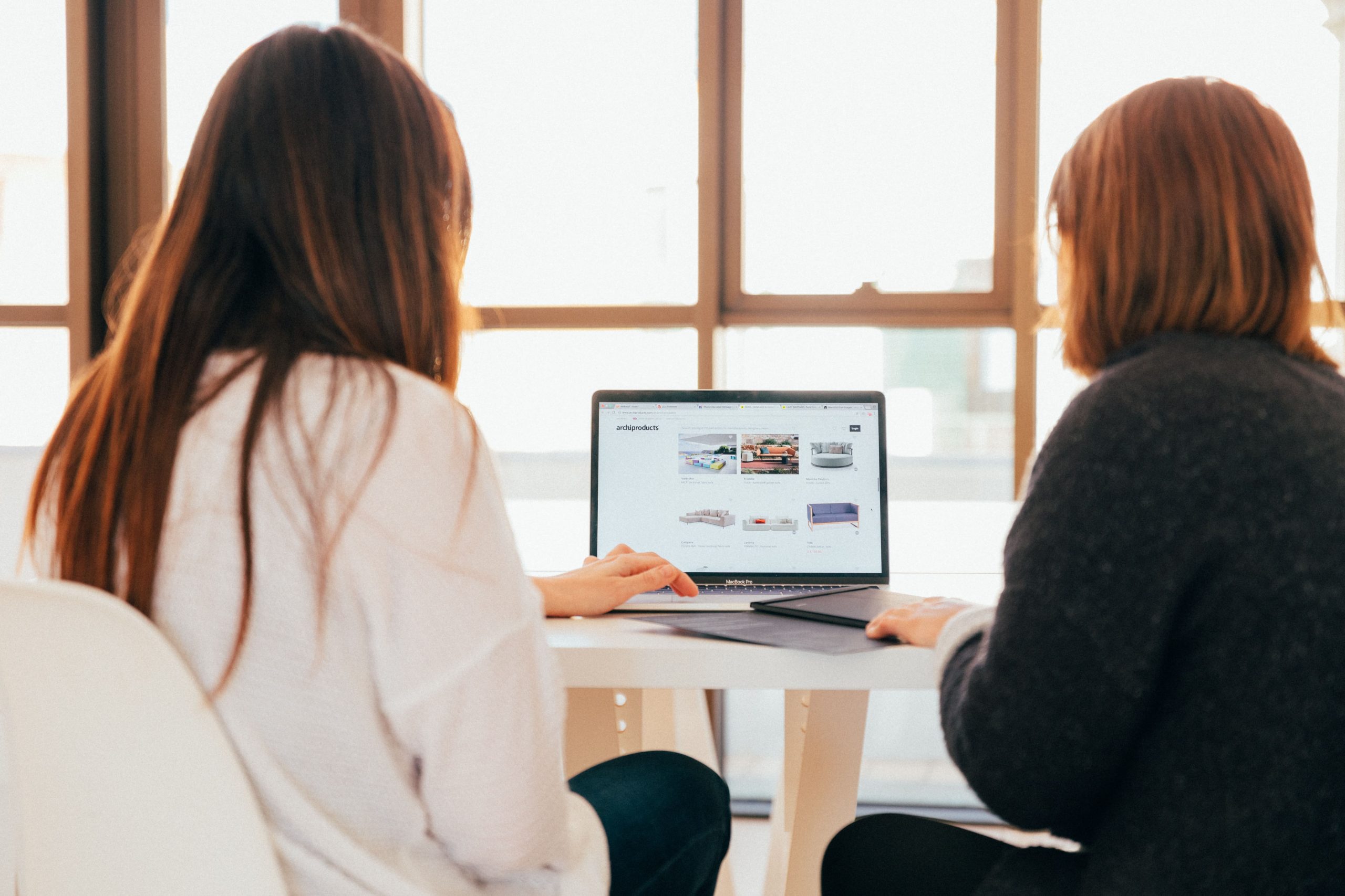 Two women sitting at a table looking at a laptop screen