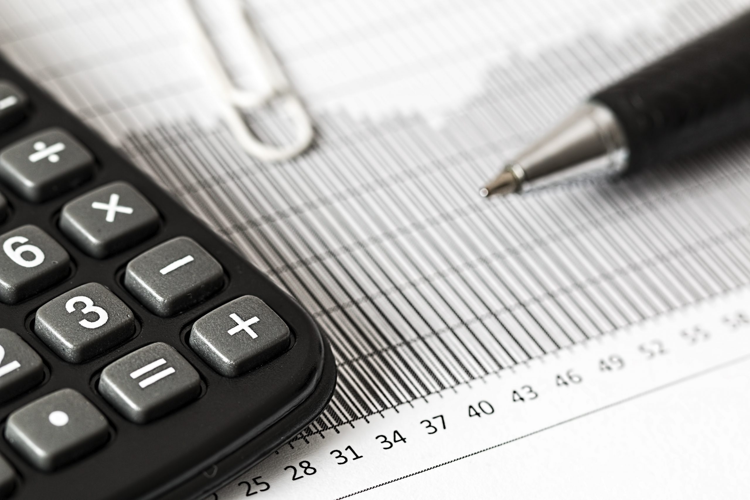 photo of a calculator and pen resting on top of a spreadsheet