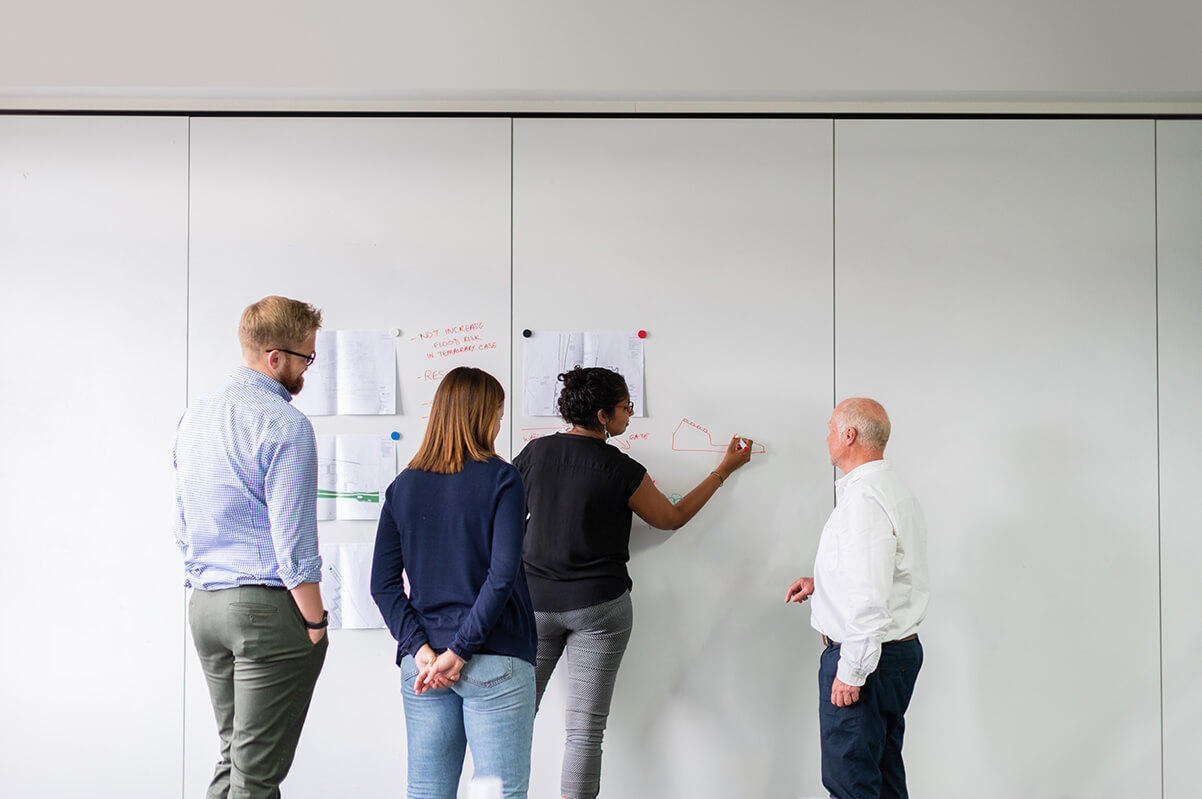 Corporate team meeting in front of a board discussing