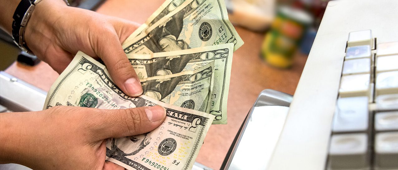 cashier holding money in front of cash register